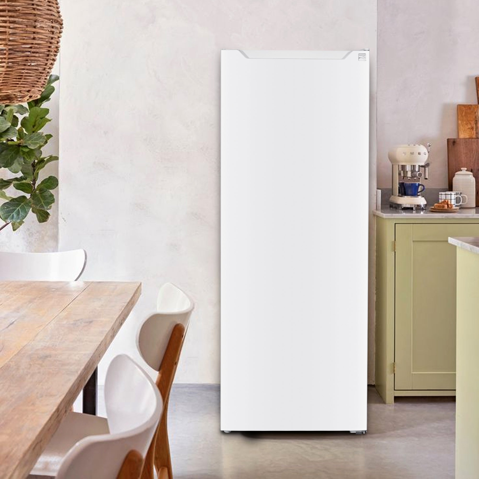 Kenmore 7 cubic foot convertible upright freezer refrigerator in a kitchen with a wooden table and chairs in the foreground and yellow cabinets to the right.